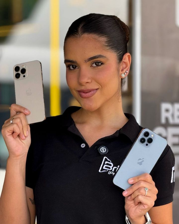 Atendente na fachada da loja com um iPhone dourado e um azul-sierra